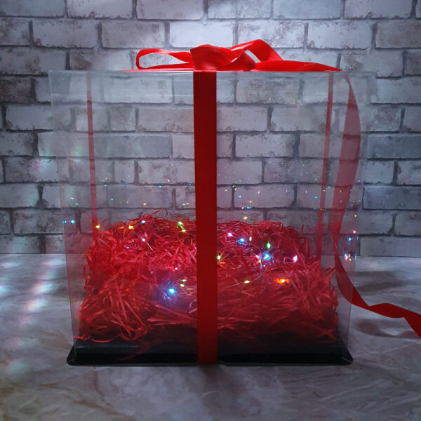 Transparenter Geschenkkarton mit rotem Band und LED-Beleuchtung